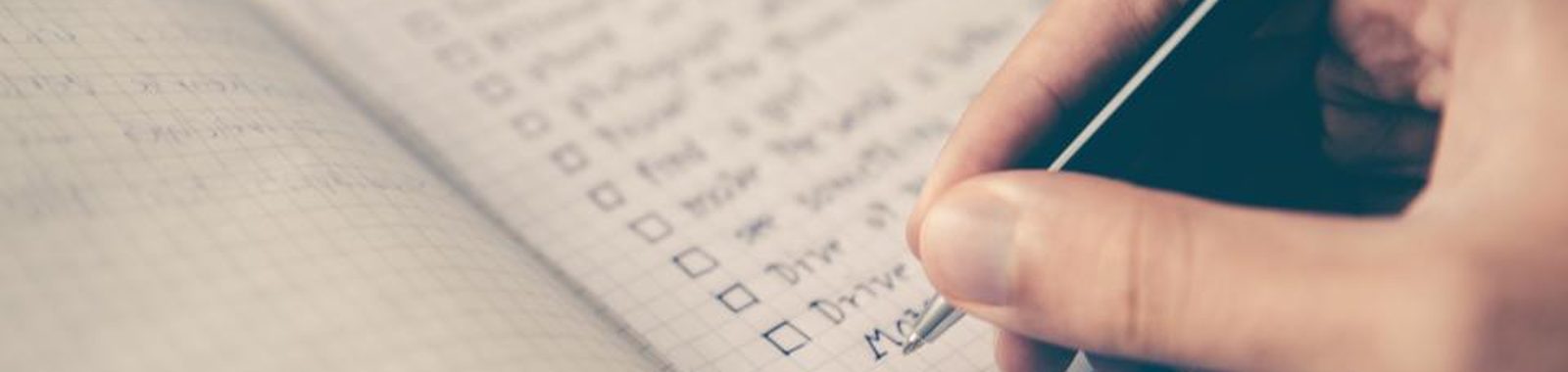 A hand writing and ticking off items on a checklist